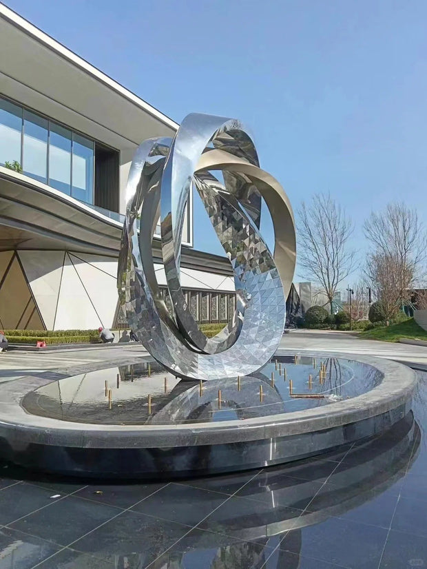 Edelstahlskulptur Ringpaar über Wasserbecken